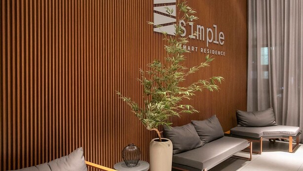 Un área de espera moderna con un panel de madera, una recepción y sofás y sillones.