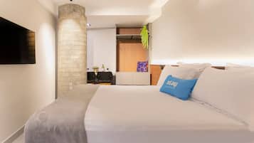 Habitación de hotel moderna con una cama grande, un televisor de pantalla plana en la pared, un pilar de piedra y un escritorio pequeño con una silla.