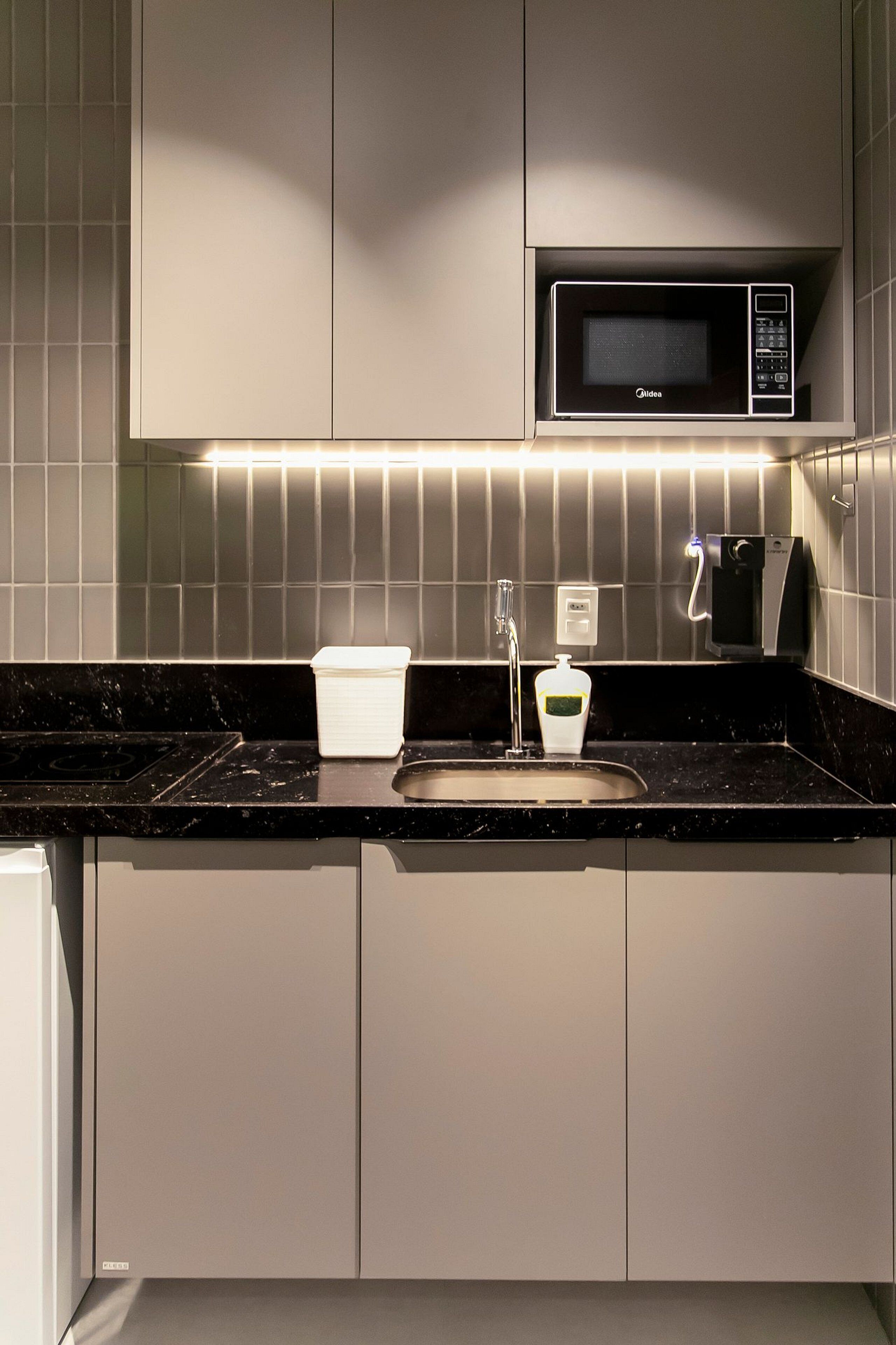 A modern kitchen with a built-in microwave, a sink, and a soap dispenser.
