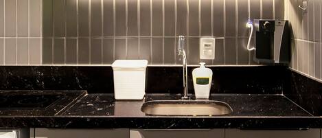 A modern kitchen with a built-in microwave, a sink, and a soap dispenser.