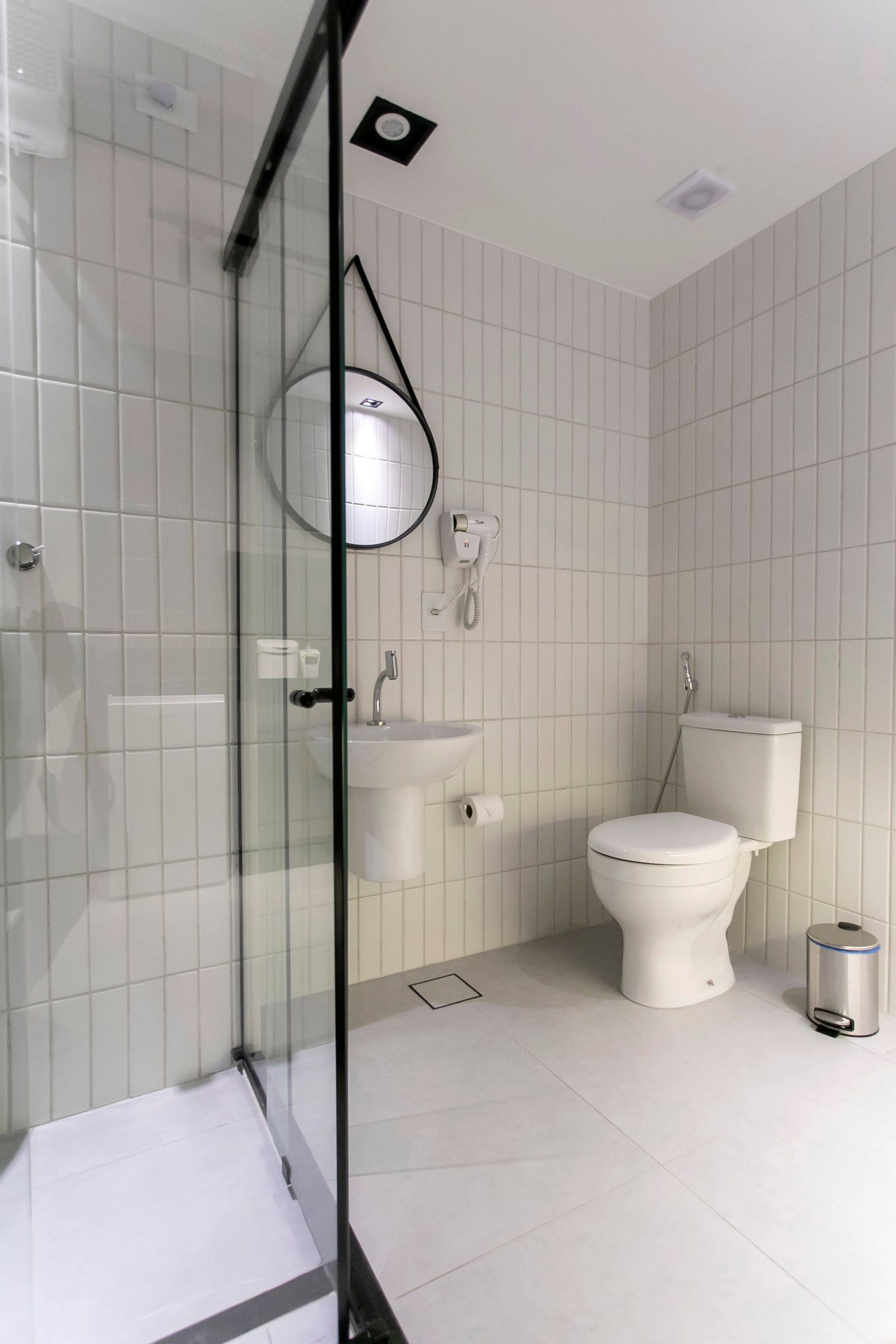 Ein modernes Badezimmer mit Duschkabine aus Glas, Toilette, Waschbecken und Mülleimer.