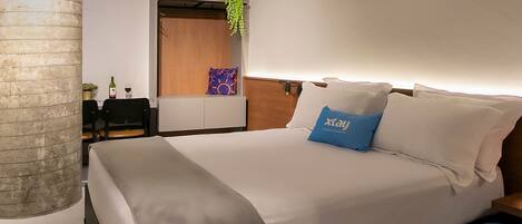 A modern hotel room with a bed, bedside table, and an air conditioning unit.