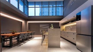 Una cocina moderna con una isla central, electrodomésticos integrados y un comedor con una mesa larga y sillas.