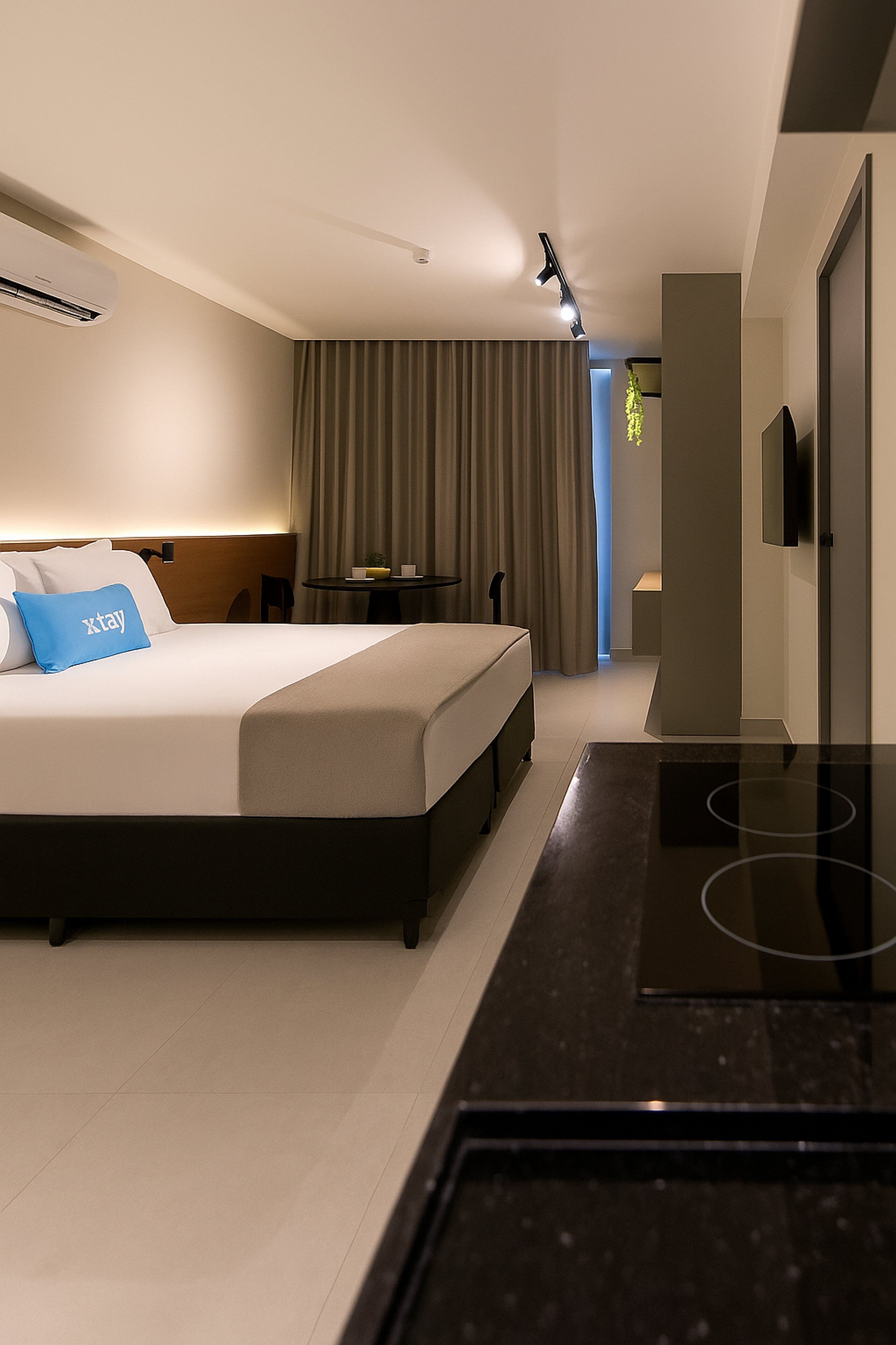 A modern hotel room with a bed, bedside table, and a flat-screen TV.
