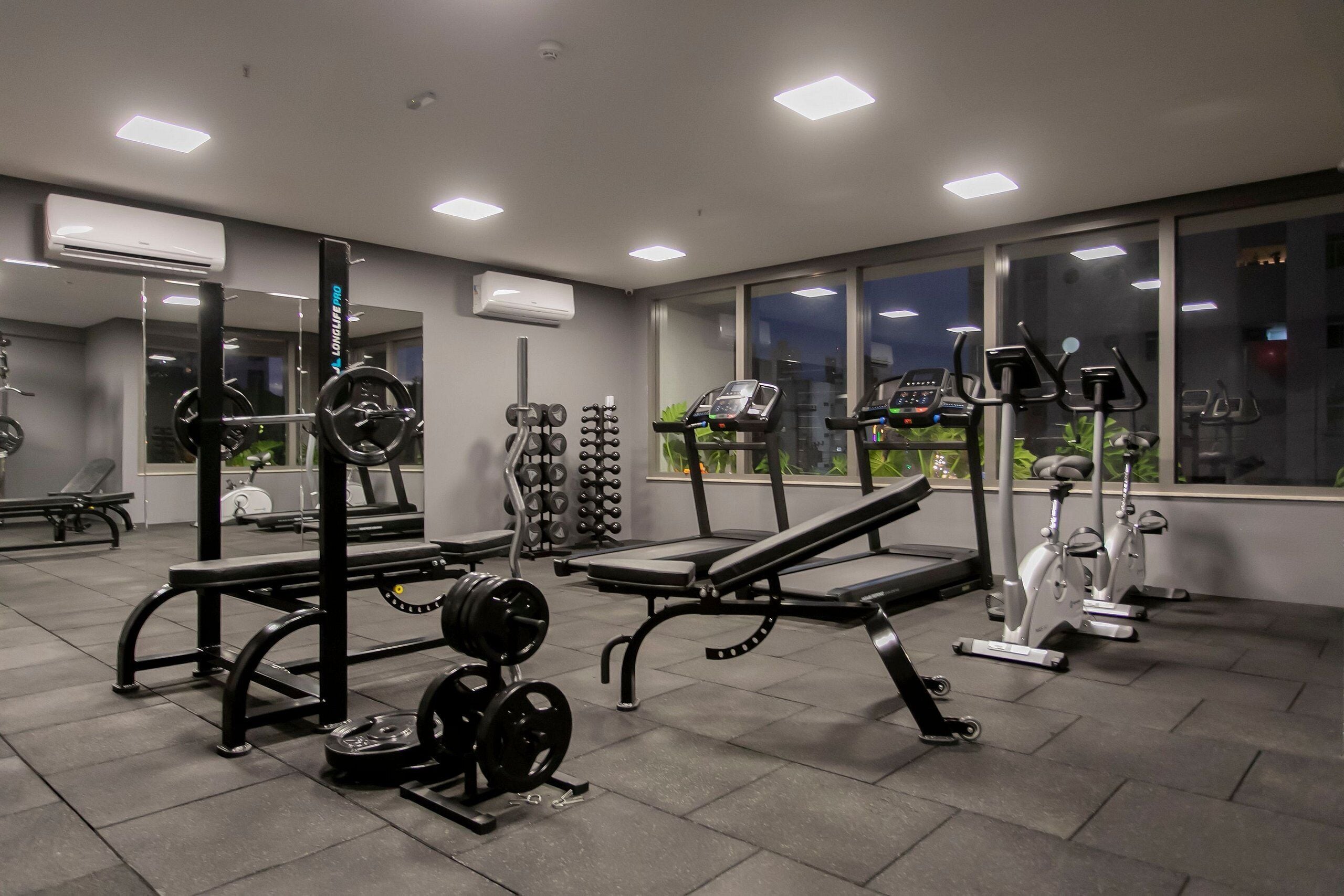 Un gimnasio con equipo de levantamiento de pesas, cintas de correr y bicicletas estáticas.