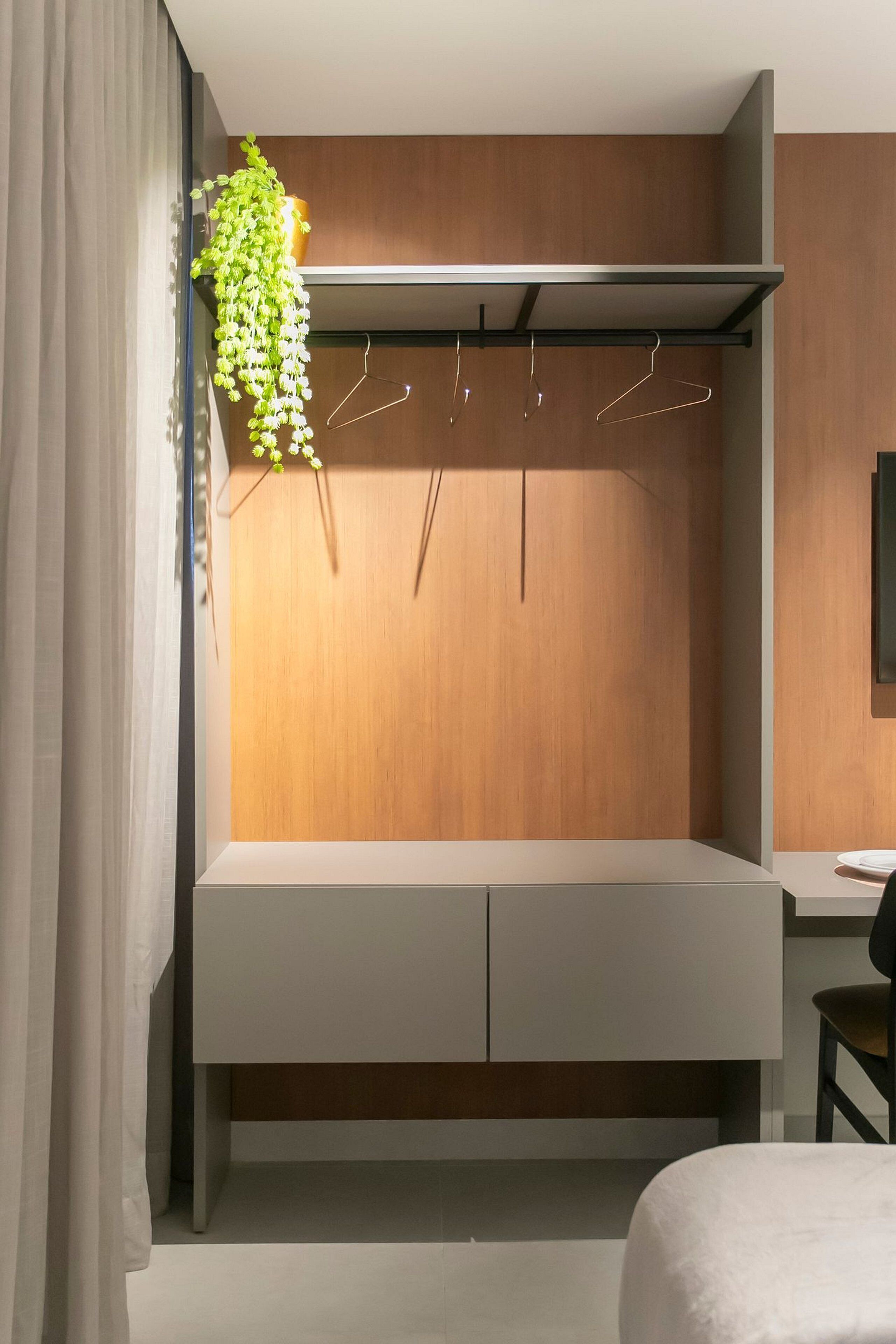 A modern bedroom with a built-in wardrobe, a hanging plant, and a desk area.