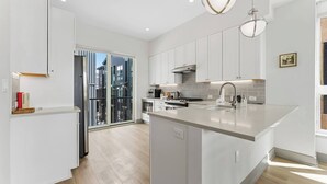 A modern kitchen with white cabinetry, a large island with a sink, and a view through a glass door to an outdoor balcony. - Contemporary luxury in the heart of Silverthorne (Silverthorne)