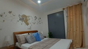 Une chambre à coucher comprenant un lit, une table de chevet et un climatiseur fixé au mur.