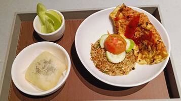 A meal consisting of fried rice with vegetables, a piece of omelette, and a dumpling on a tray.