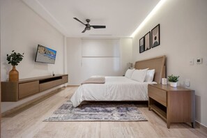 A modern bedroom with a bed, bedside tables, a ceiling fan, a TV, and a large window. - Arch views, 2 pools, 2 Jacuzzis, Gym, 3 King Beds (Cabo San Lucas)