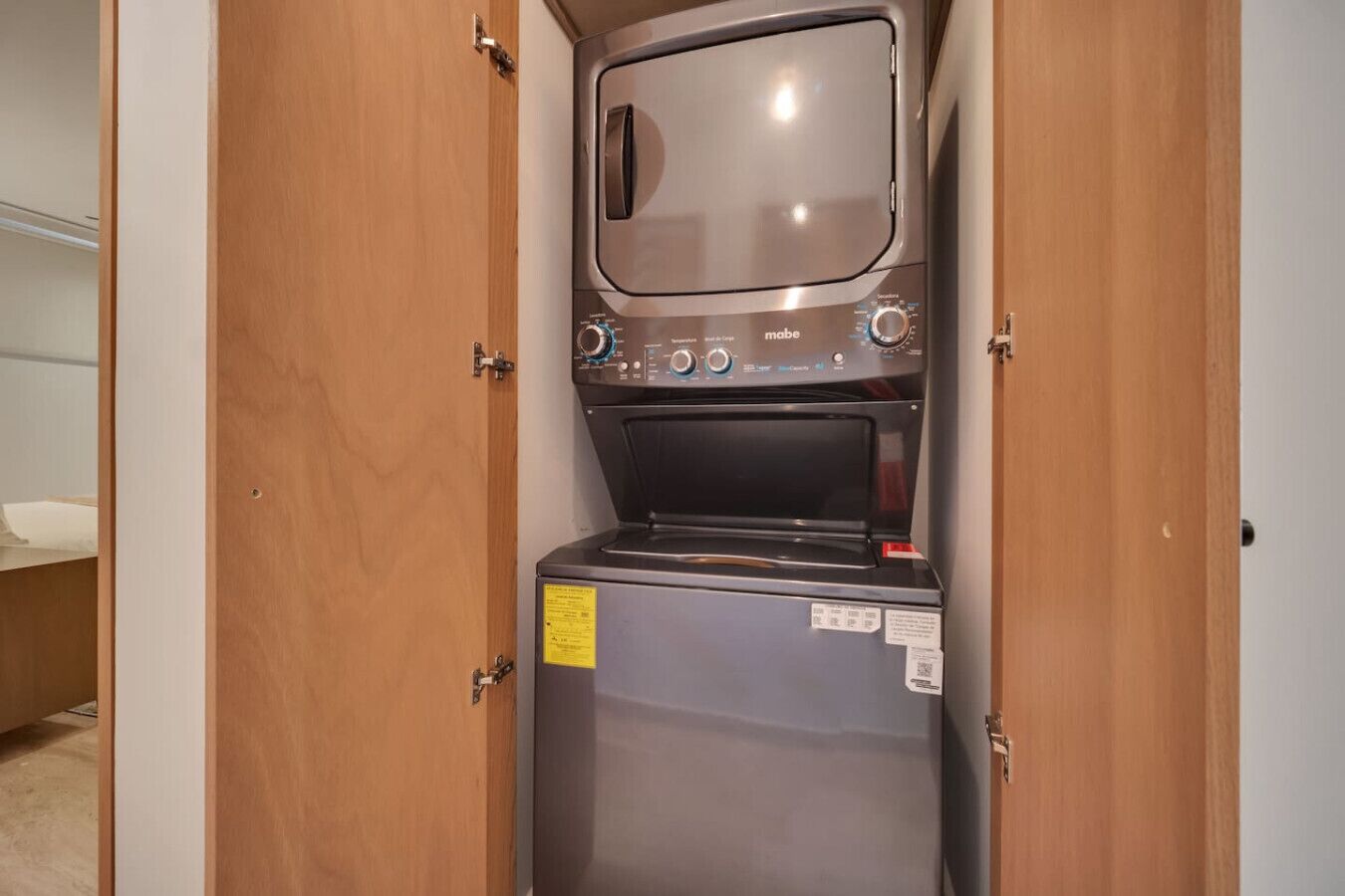 A compact washer and dryer unit with a control panel, installed in a narrow hallway.