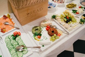 Una mesa de buffet con diversos alimentos, incluyendo queso, uvas y pepinos en rodajas.