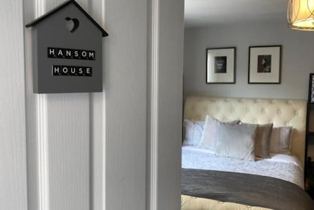 A bedroom with a tufted headboard, a bed with white linens, and two framed pictures on the wall.