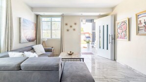 A modern living room with a grey sofa, a small table, and artwork on the walls. - Beachside Near Airport Near Golf Course (Aguadilla)