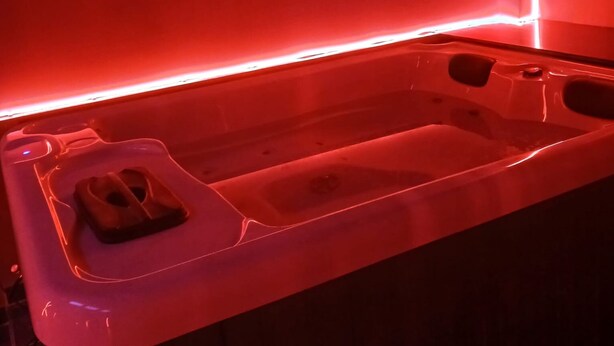 A hot tub with a built-in seat and a small table, surrounded by a wooden structure. - la chambre des plaisirs secrets Manduel (Manduel)
