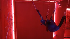 A room with red walls, a hanging swing, and a brick wall in the background. - la chambre des plaisirs secrets Manduel (Manduel)