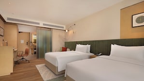 Habitación de hotel con dos camas, un escritorio y una silla.