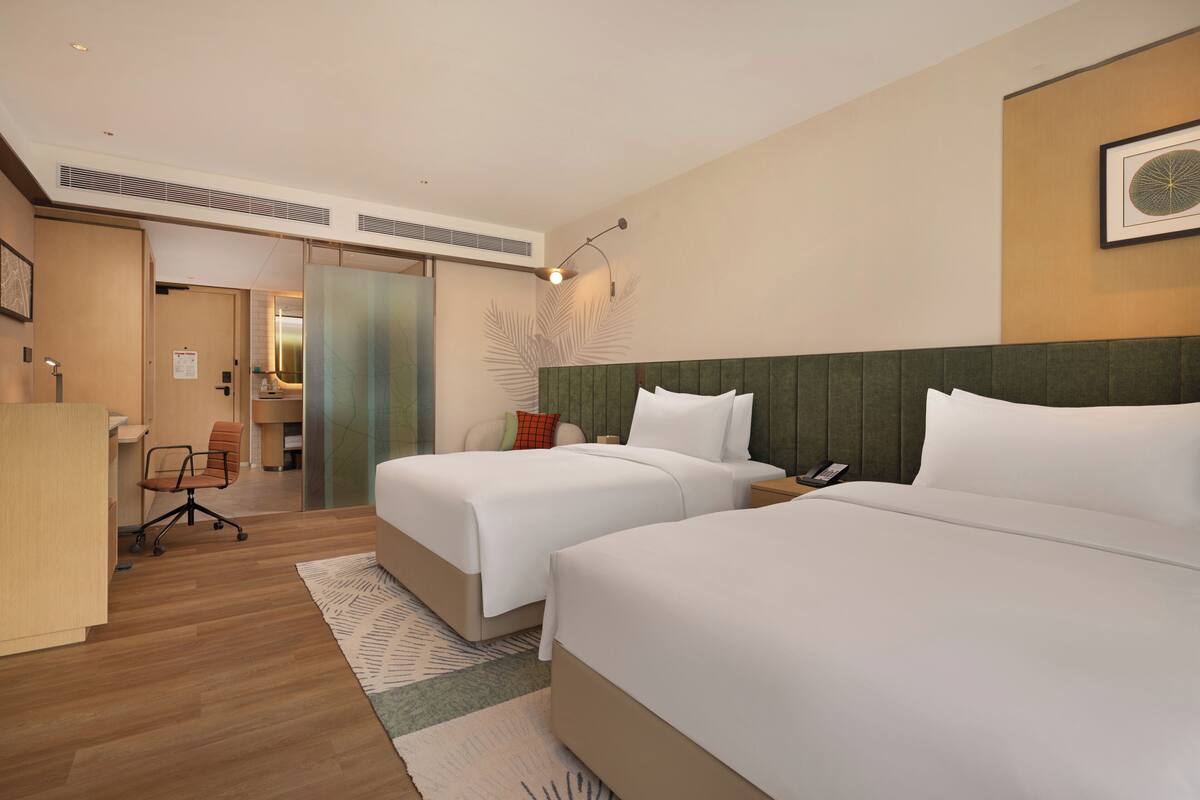 Habitación de hotel con dos camas, un escritorio y una silla.