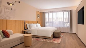 Una habitación de hotel moderna con cama, sofá, una mesita y televisor.