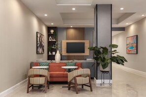 A modern living room with a sofa, two striped chairs, a coffee table, a flat-screen TV, decorative items, and a large plant.