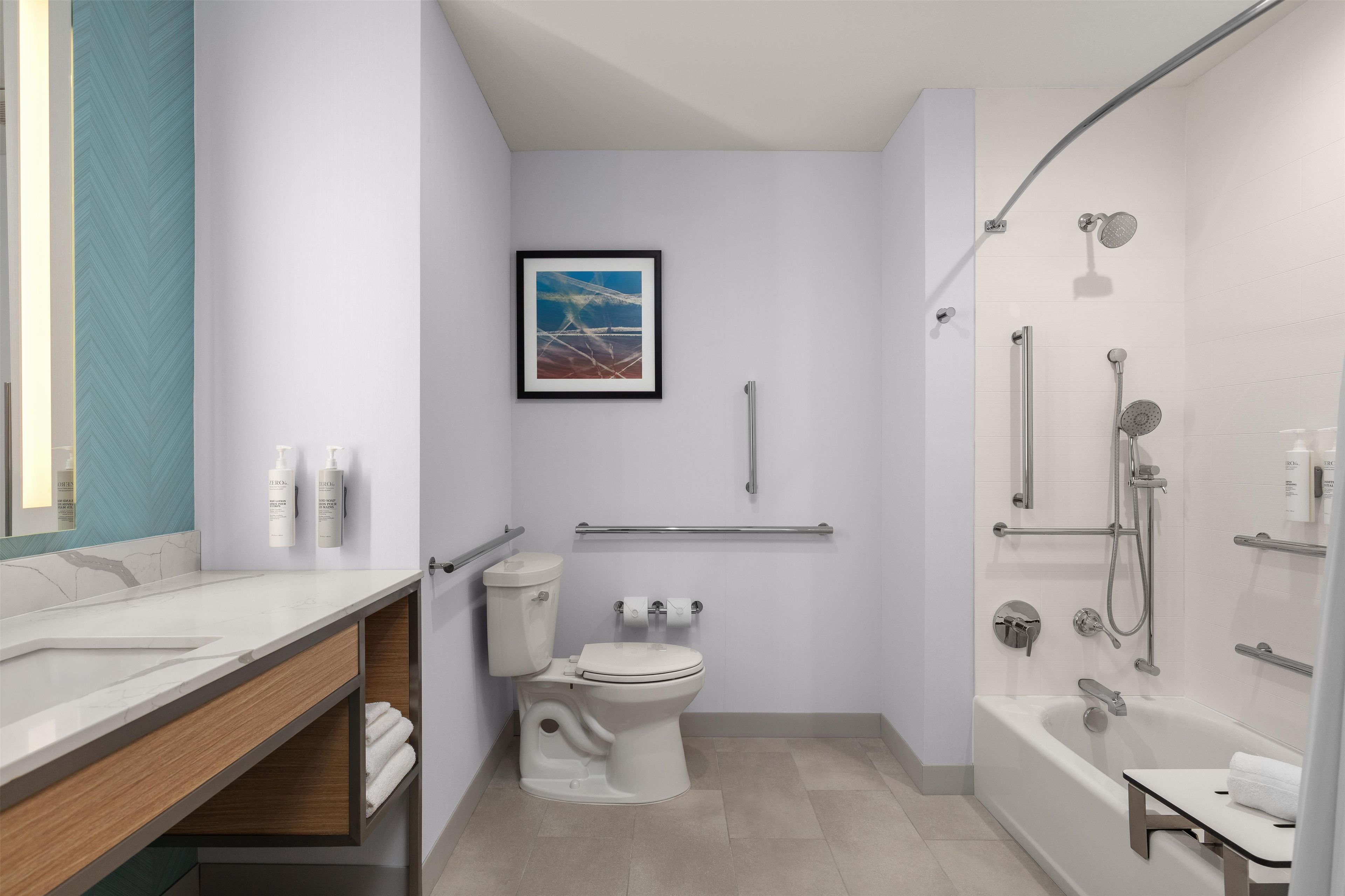 Un baño moderno con inodoro, lavamanos, ducha y un cuadro en la pared.