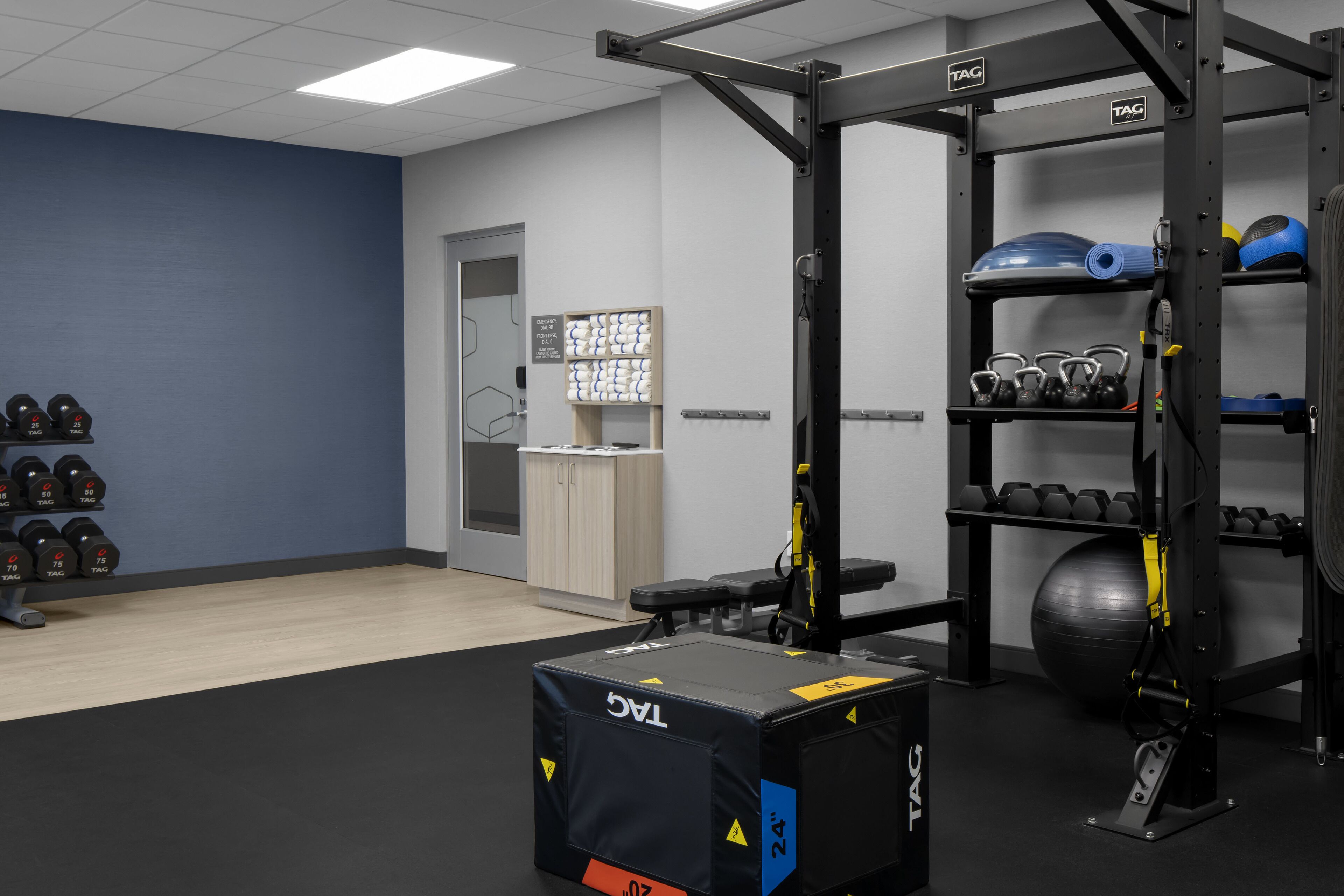 A gym with weightlifting equipment, dumbbells, kettlebells, and exercise balls.