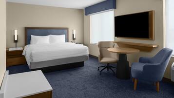 A hotel room with a bed, bedside tables, a desk, a chair, a TV, and a window.