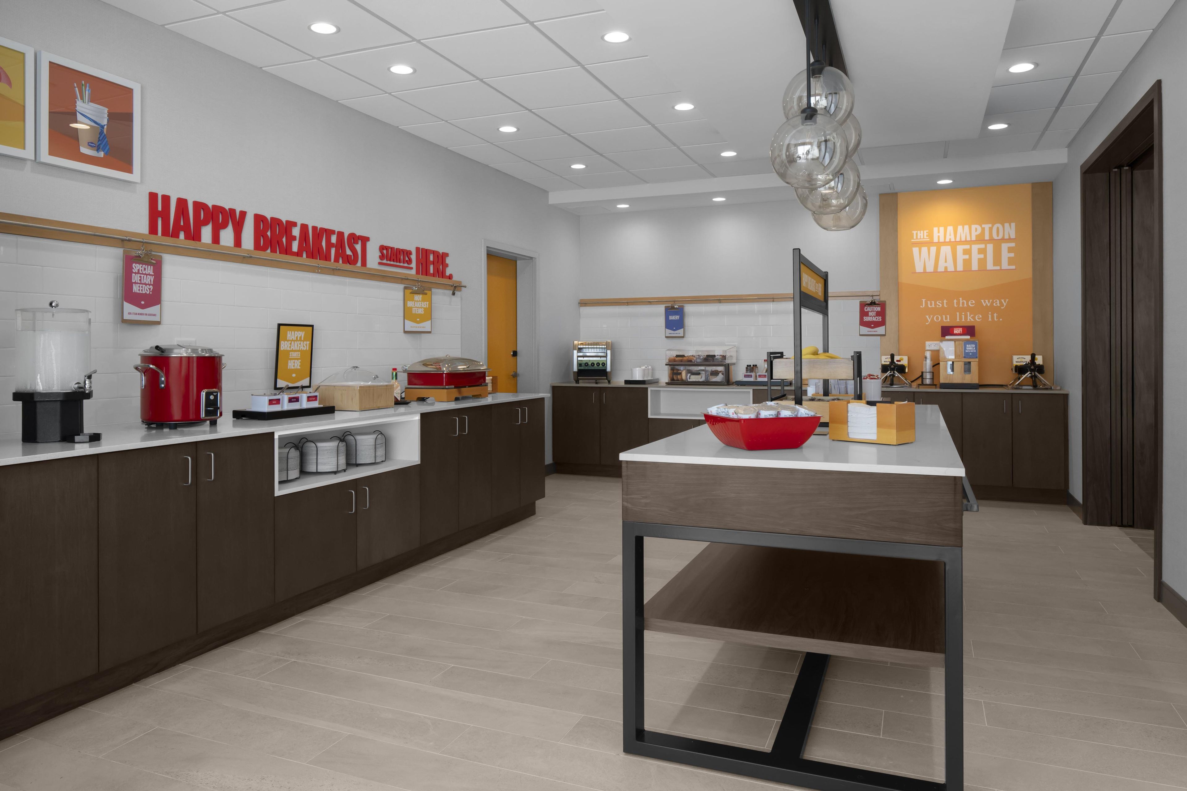 A modern breakfast area with a counter, kitchen appliances, and a waffle station.