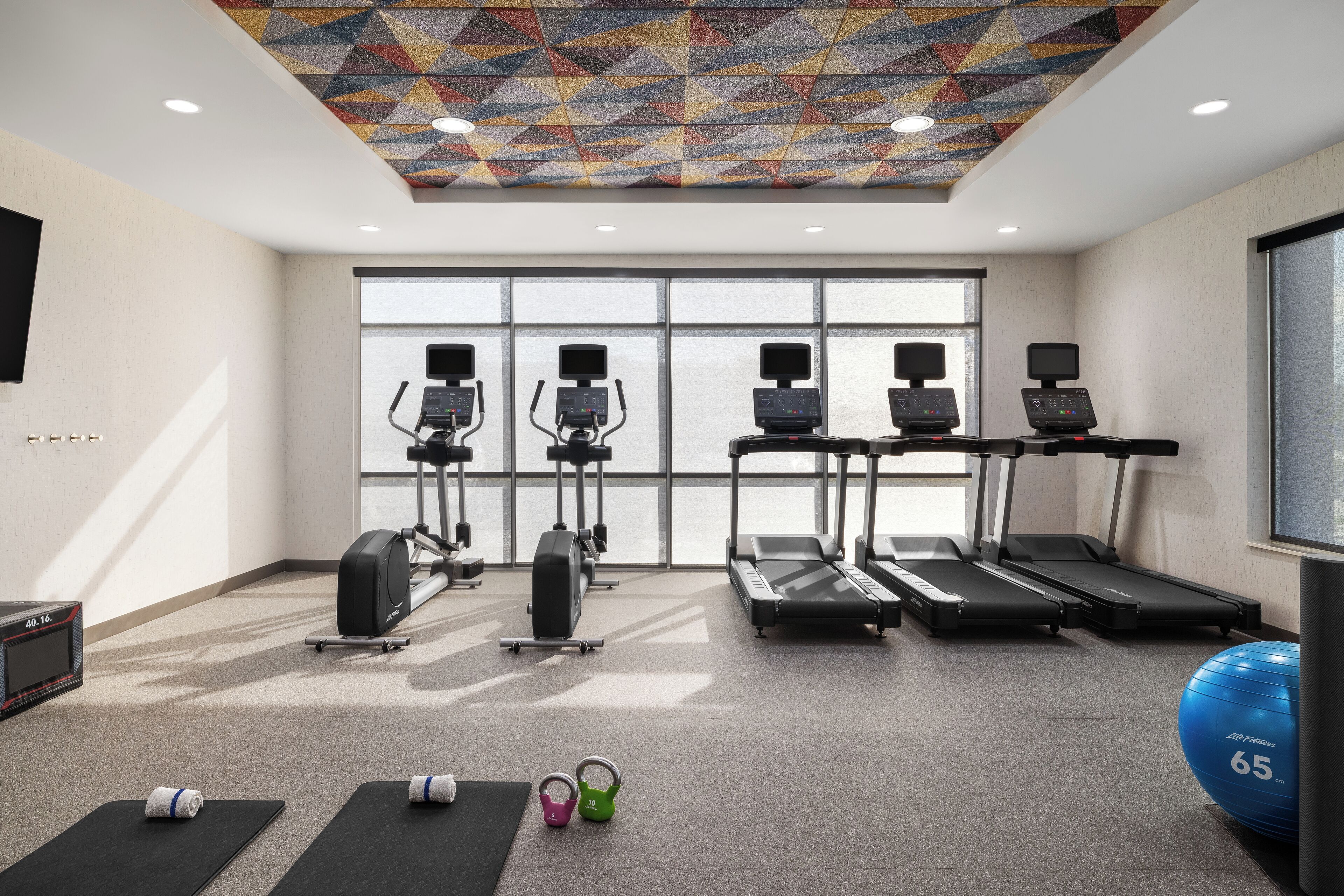 Un gimnasio con cintas de correr, elípticas y pesas sueltas.