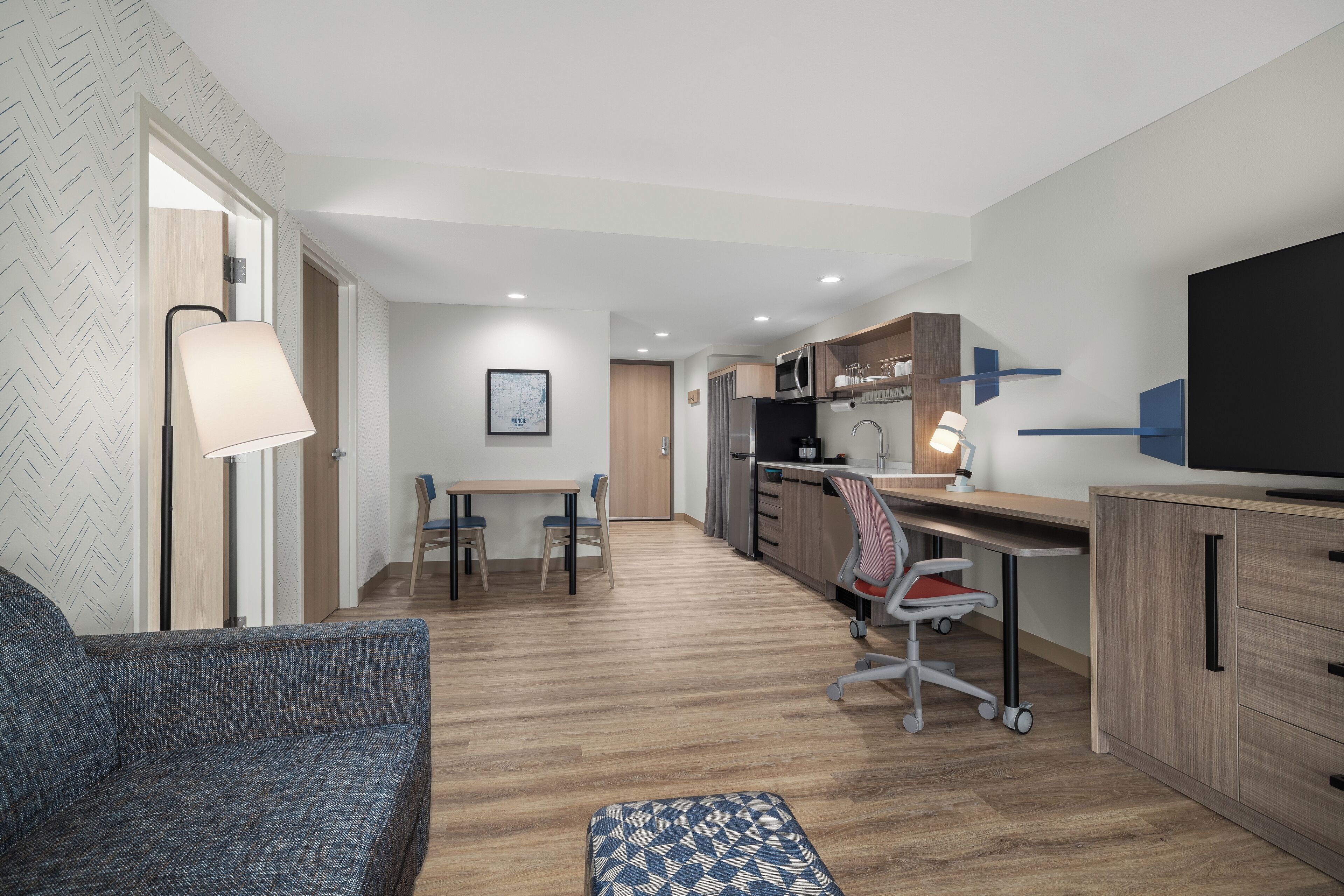 A modern, compact living space with a sofa, a dining table, a kitchen area, and a television.