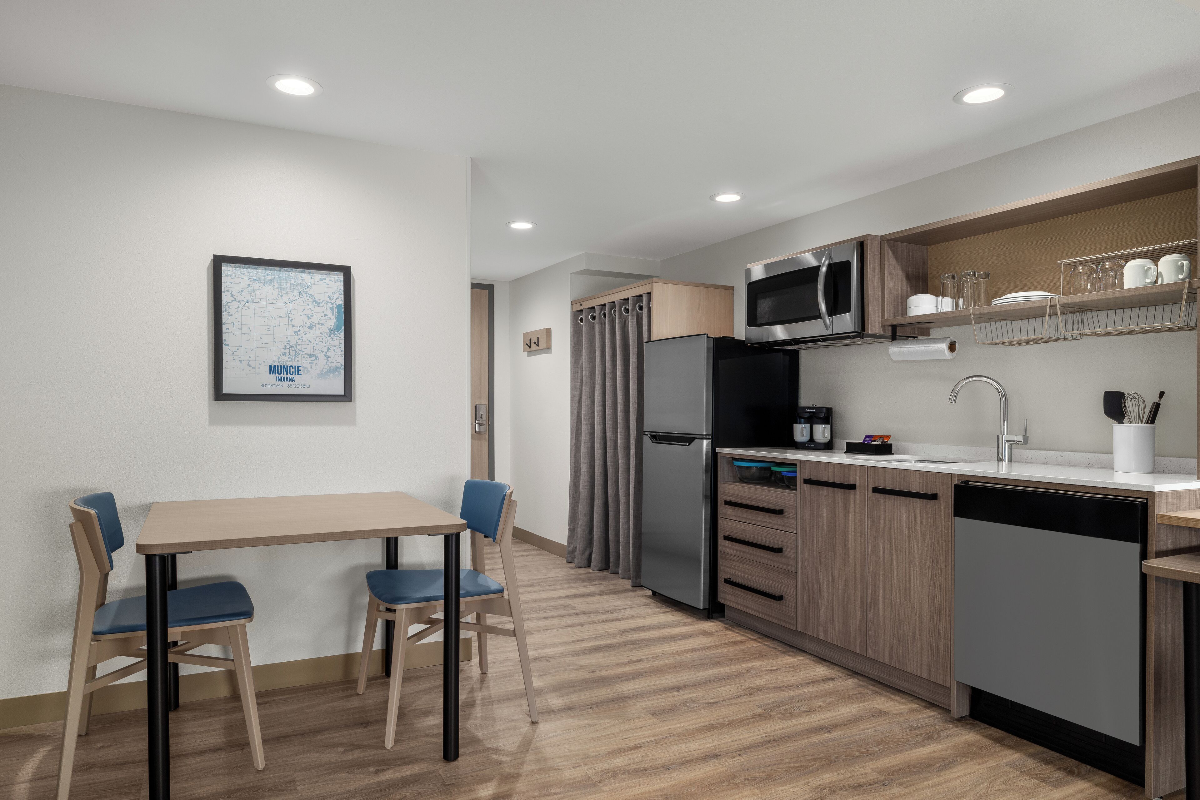 Una cocina moderna con comedor, electrodomésticos de acero inoxidable y un mapa en la pared.