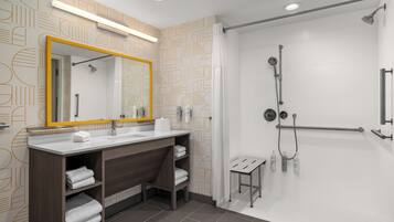 Un baño moderno con un espejo grande, dos lavamanos, una zona de ducha y un taburete pequeño.