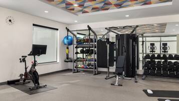 A gym with exercise equipment, a wall clock, and a window.