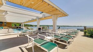 A poolside area with lounge chairs, a pool, and a view of the water. - Lakefront 1 bdrm—Pool & Hot Tub—Lake Michigan Access—2 Kayaks Provided! (Onekama)