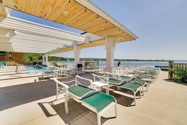 A poolside area with lounge chairs, a pool, and a view of the water.