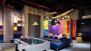 A modern lounge area with a foosball table, colorful seating, and ambient lighting. - Tru by Hilton Tam Ky City Centre (Da Nang)