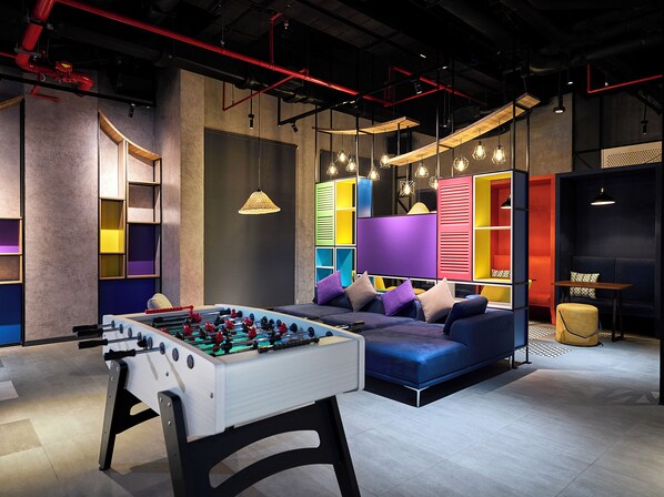 A modern lounge area with a foosball table, colorful seating, and ambient lighting. - Tru by Hilton Tam Ky City Centre (Da Nang)
