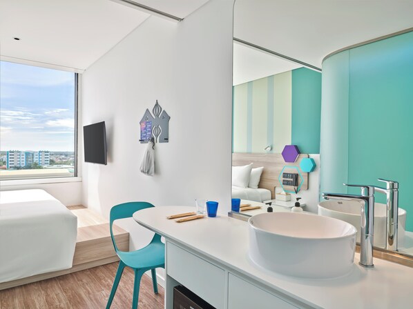 A modern hotel room with a large window, a white bed, a white sink, and a teal chair. - Tru by Hilton Tam Ky City Centre (Da Nang)