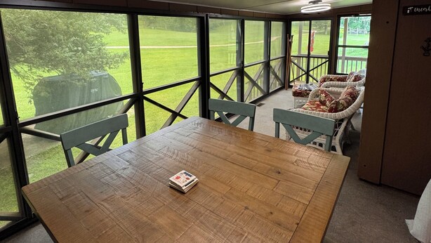 A wooden table with a book, a ceiling light, and large windows with a view of a grassy area. - Woodson Bend 3 BR Condo 82-4, with  AC, WiFi, Pool, Golf Course, Restaurant (Bronston)