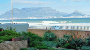 A coastal view with a mountain in the background, a white fence, and some greenery in the foreground. - Sea View Zeezicht, Bloubergstrand, Blouberg Beach, Cape Town (Bloubergstrand)