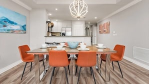Un comedor moderno con una mesa de madera, cuatro sillas naranjas y una lámpara colgante original.