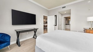 Una habitación de hotel moderna con una cama grande, un televisor de pantalla plana montado en la pared, un escritorio y una silla azul.