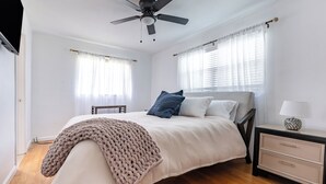 A bedroom with a bed, bedside table, and a ceiling fan.