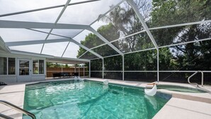 A swimming pool with a glass enclosure, clear water, and a sunshade structure.