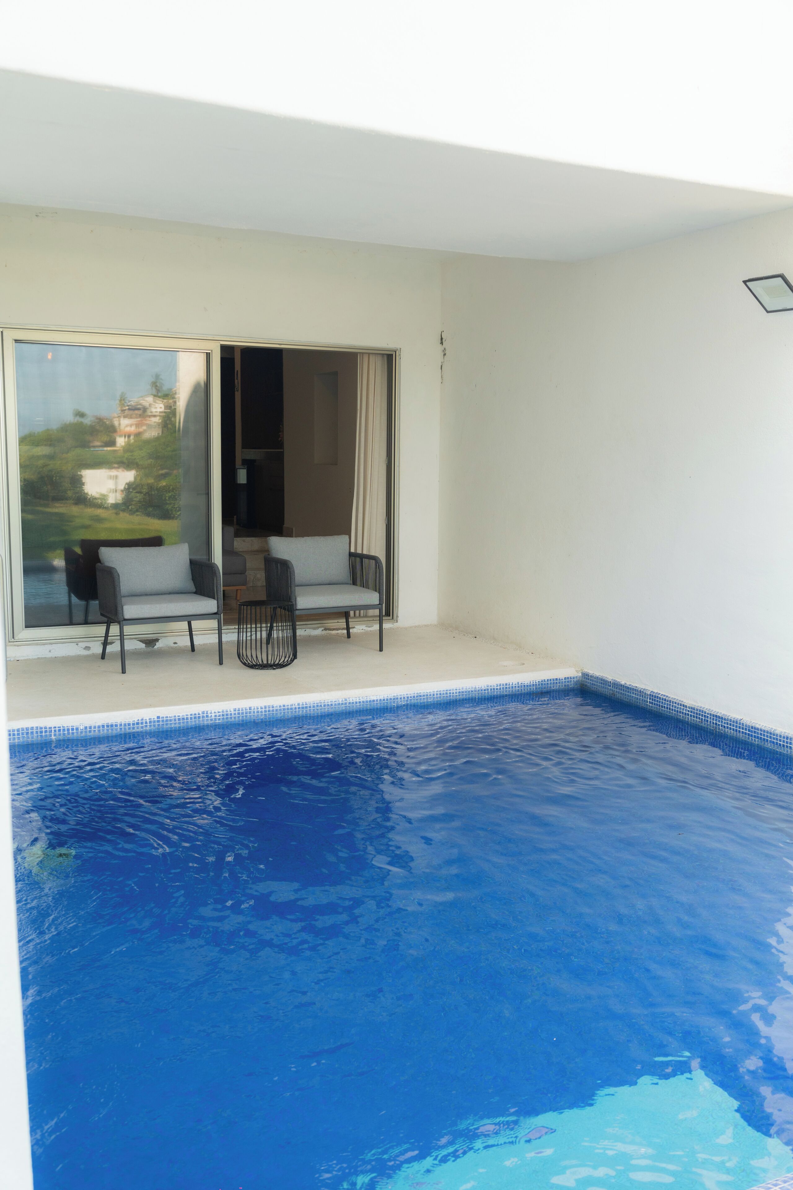 A swimming pool with a view of a building and a chair outside.