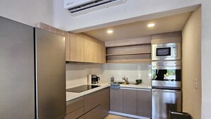 A compact kitchen with a built-in refrigerator, microwave, and oven. - Departamento en Bahias de Huatulco (Santa Maria Huatulco)