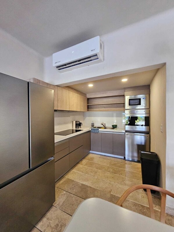 A compact kitchen with a built-in refrigerator, microwave, and oven. - Departamento en Bahias de Huatulco (Santa Maria Huatulco)