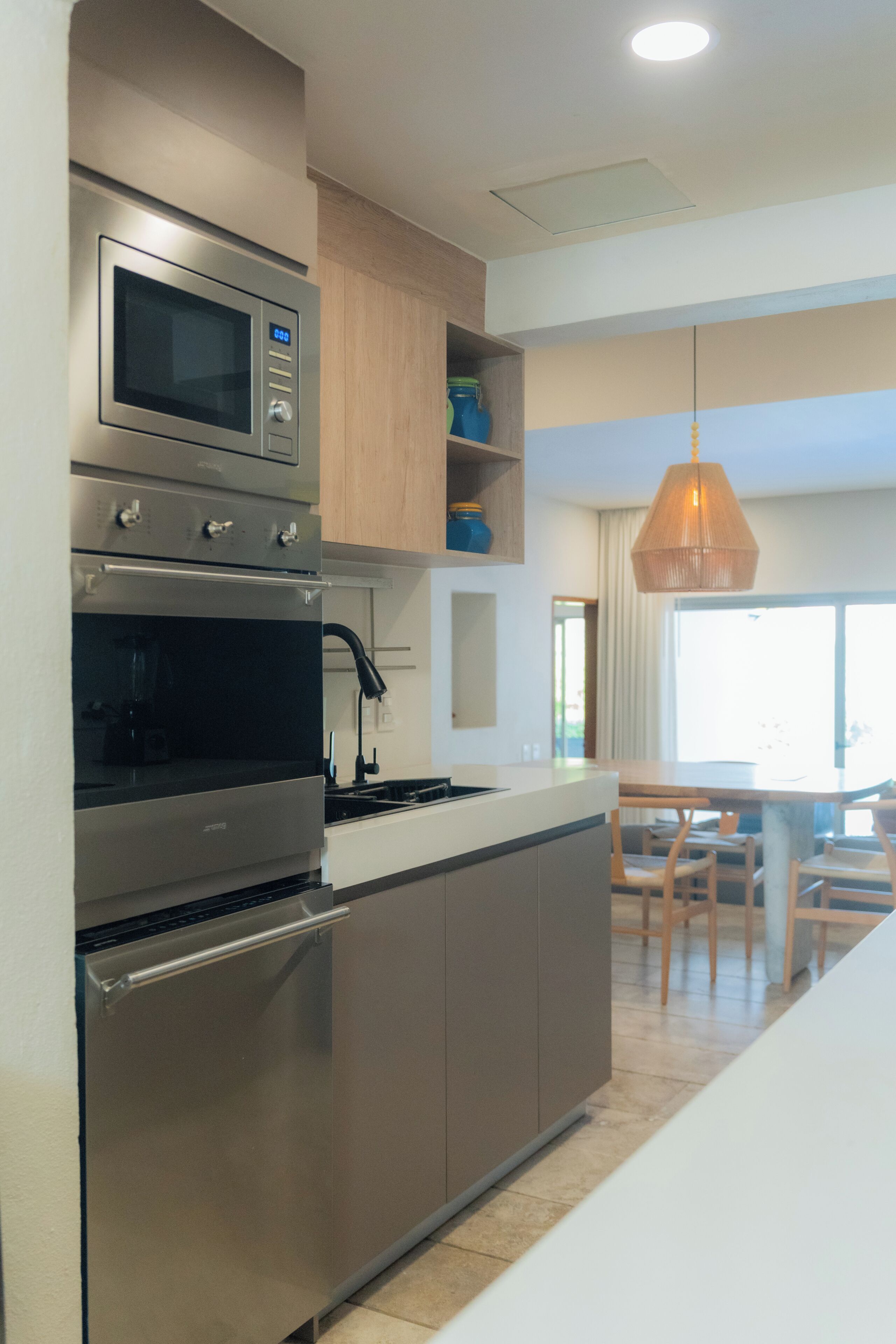 Una cocina moderna con electrodomésticos de acero inoxidable, armarios de madera y una lámpara colgante.