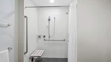 Un espace douche équipé d’une barre d’appui, d’un pommeau de douche à main et d’un drain au sol.