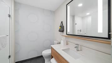 A modern bathroom with a large mirror, white sink, and toilet.
